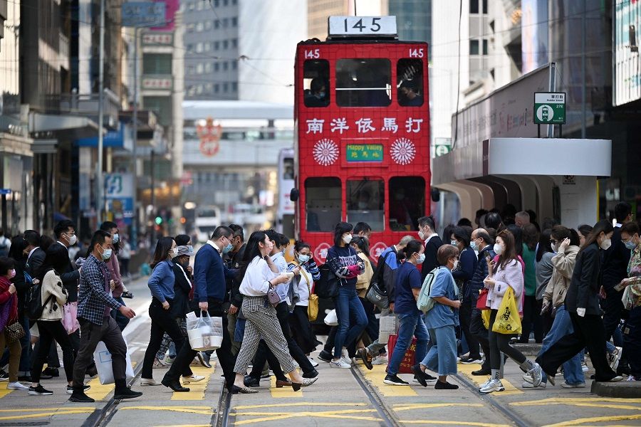 This photo taken on 21 February 2023 shows pedestrians crossing a street in the Central district of Hong Kong, China. (Peter Parks/AFP)