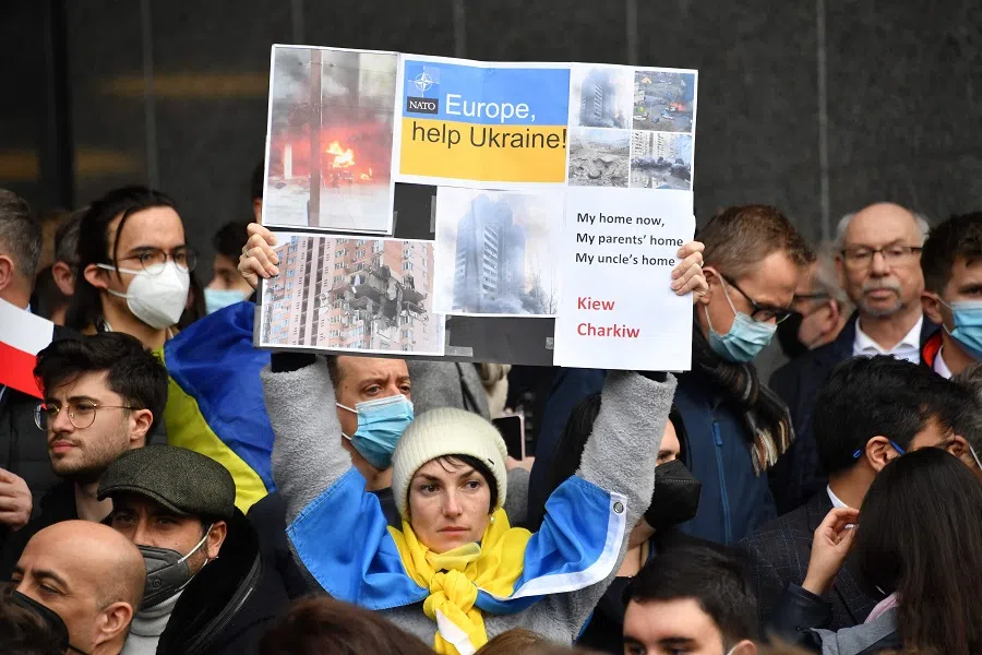 A demonstrator holds a banner in front of the European Parliament after a special plenary session on the Russian invasion of Ukraine at the EU headquarters in Brussels, Belgium, on 1 March 2022. (John Thys/AFP)