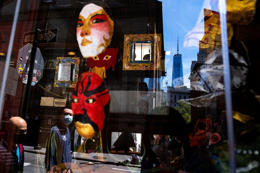 A man wearing a protective mask is reflected on a window in Chinatown during the Covid-19 outbreak in New York City, New York, US, on 17 May 2020. (Jeenah Moon/Reuters)