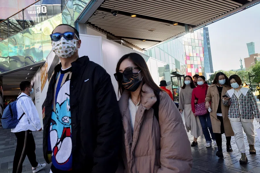 People walk in an upscale shopping district in the Sanlitun area in Beijing, China, 19 October 2021. (Thomas Peter/Reuters)