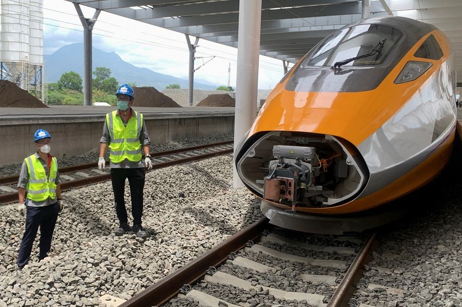 Workers stand beside an Electric Multiple Unit high-speed train for a rail link project part of China's Belt and Road Initiative, at Tegalluar train depot in Bandung, Indonesia, 13 October 2022. (Yuddy Cahya Budiman/Reuters)