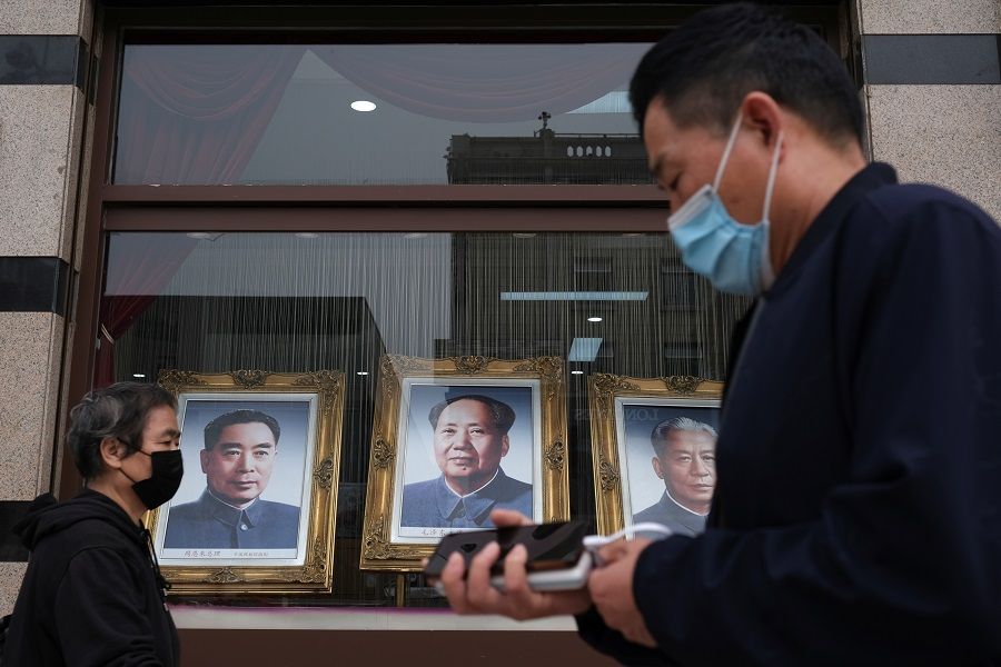 People wearing face masks walk past portraits of late Chinese Communist Party leaders (left to right) Zhou Enlai, Mao Zedong and Liu Shaoqi, in Beijing, China on 7 May 2020. (Carlos Garcia Rawlins/Reuters)