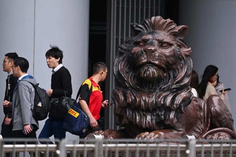 People walk past one of two bronze lions outside the HSBC building in Hong Kong on 19 February 2025. (Peter Parks/AFP)