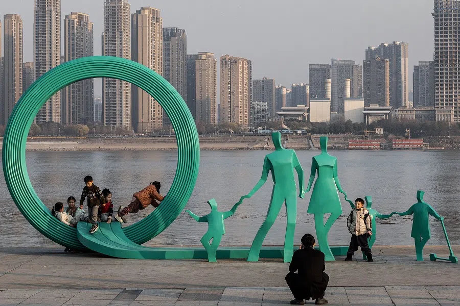 This photo taken on 5 January 2024 shows people posing next to a newly renovated statue of a pair of parents and three children in Wuhan, Hubei province, China. (AFP)