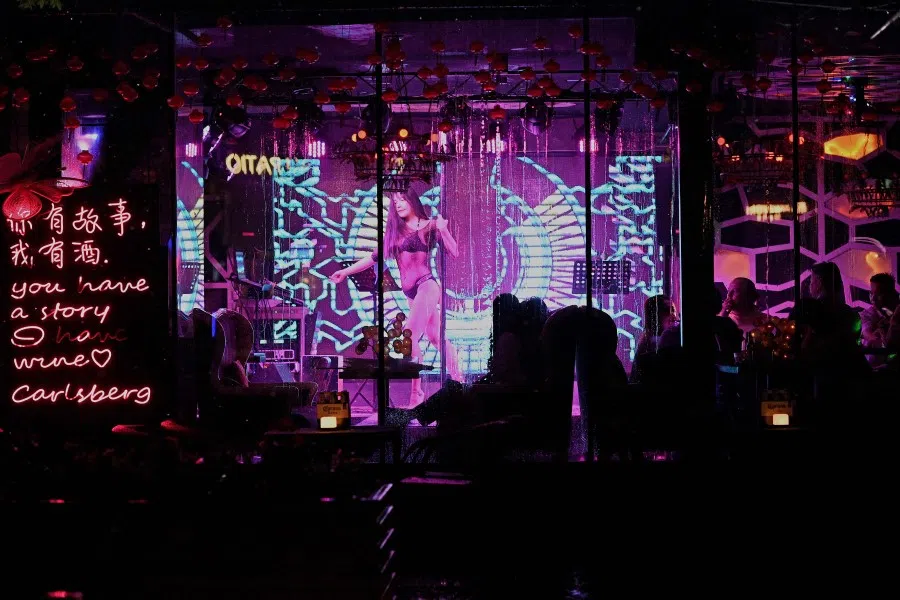 People watch as a dancer performs on stage at a bar in Beijing on 23 August 2021. (Noel Celis/AFP)