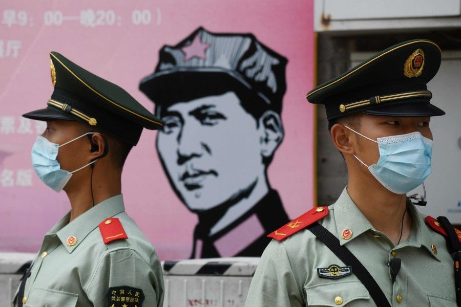 Paramilitary police officers stand guard in front of a poster of late communist leader Mao Zedong on a street south of the Great Hall of the People during the opening session of the National People's Congress (NPC) in Beijing on May 22, 2020. (Greg Baker/AFP)