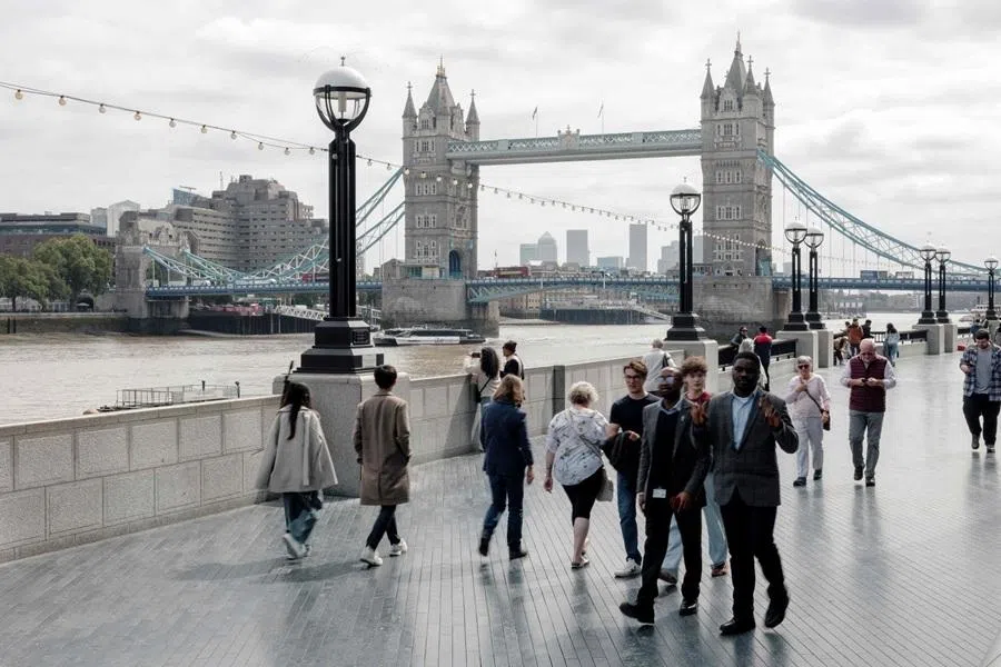 People walk along the south bank of the River Thames, past Tower Bridge (behind), in central London on 21 May 2026.