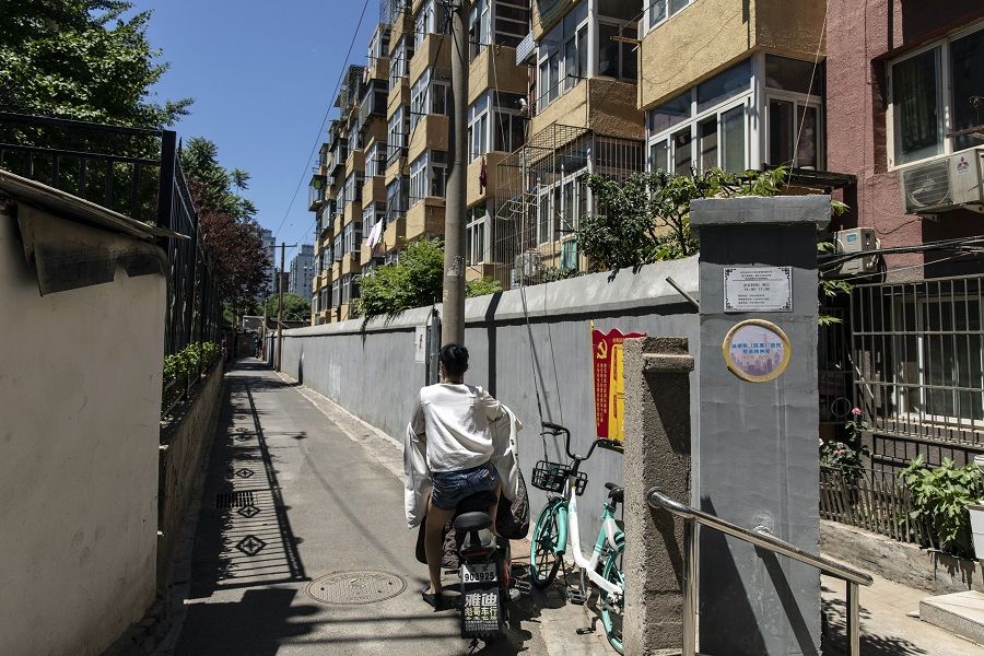 A motorist sits on a motorcycle in front of apartment buildings in a residential area in Beijing, China on 28 May 2021. (Qilai Shen/Bloomberg)