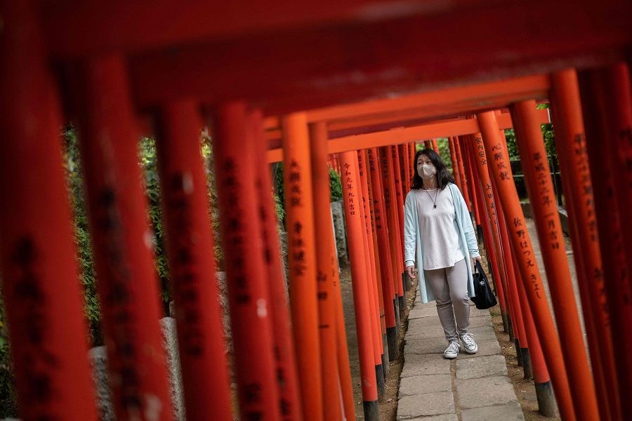 A woman walks through the Torii path at Nezu Shrine in Tokyo on 17 April 2024. (Yuichi Yamazaki/AFP)