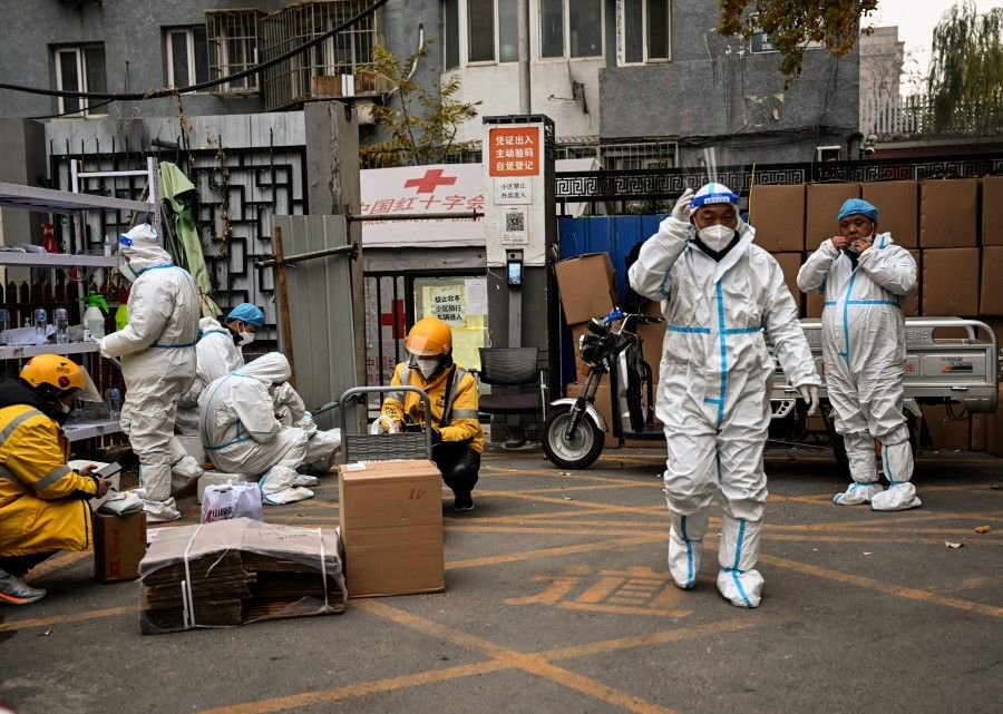 Health workers guard the entrance of a residential area under lockdown due to Covid-19 restrictions in Beijing, China, on 24 November 2022. (Noel Celis/AFP)