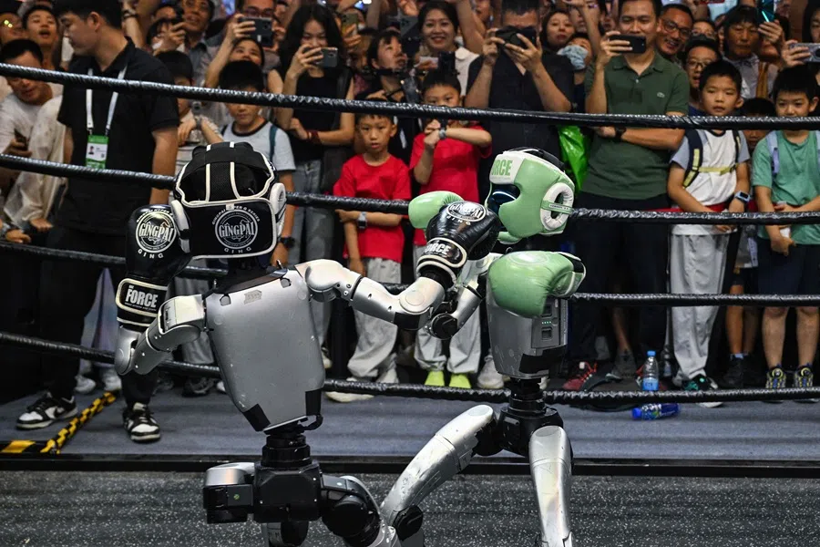 People watch remote-controlled robots by Unitree Robotics boxing during the World Artificial Intelligence Conference (WAIC) in Shanghai, China, on 28 July 2025. (Hector Retamal/AFP)