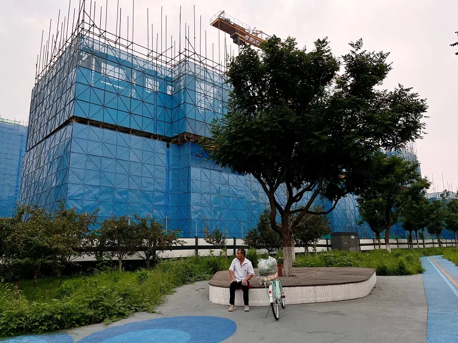 A person sits near a construction site of residential buildings by Chinese developer Country Garden, in Beijing, China, on 11 August 2023. (Tingshu Wang/File Photo/Reuters)