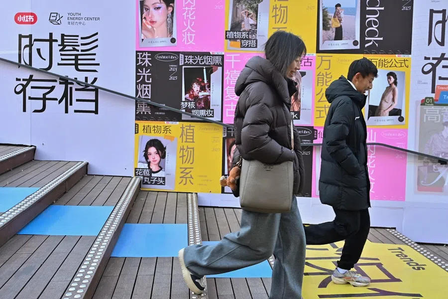 People walk past advertising for Chinese social networking and e-commerce app Xiaohongshu, also known as RedNote, at a shopping centre in Beijing, China, on 15 January 2025. (Adek Berry/AFP)