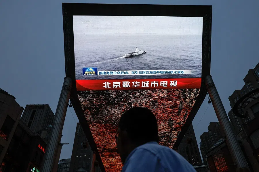 A person looks at a screen showing news footage of military drills conducted in areas around the island of Taiwan by the Eastern Theatre Command of the PLA, in Beijing, China, on 23 May 2024. (Tingshu Wang/Reuters)