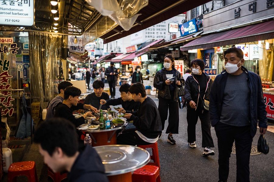Customers eat outside a restaurant in Namdaemun Market in Seoul, South Korea, on 2 November 2021. (Anthony Wallace/AFP)