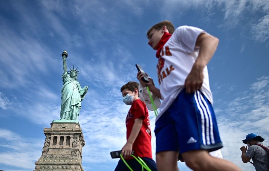 In this file photo tourists wearing facemasks walk on the reopened Liberty Island in front of the Statue of Liberty on 20 July 2020 in New York City. (Johannes Eisele/AFP)