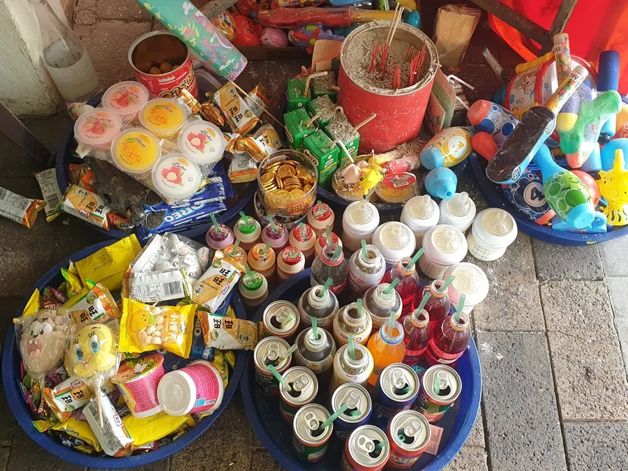 Milk bottles, lollipops and toys are among the items laid out as offerings during the Hungry Ghost Month at a coffee shop in Singapore.  (SPH Media)