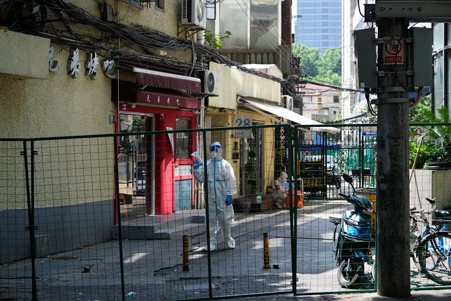 A worker in protective suit speaks through a megaphone as he directs residents of the buildings to go for nucleic acid testing at a residential area in Shanghai, China, 6 June 2022. (Aly Song/Reuters)