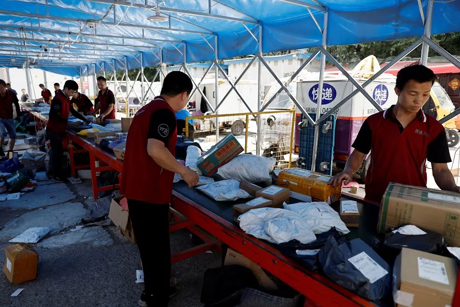 Delivery workers sort packages on a conveyor belt, ahead of the “618” shopping festival, at a logistics station in Beijing, China, 12 June 2023. (Tingshu Wang/Reuters)
