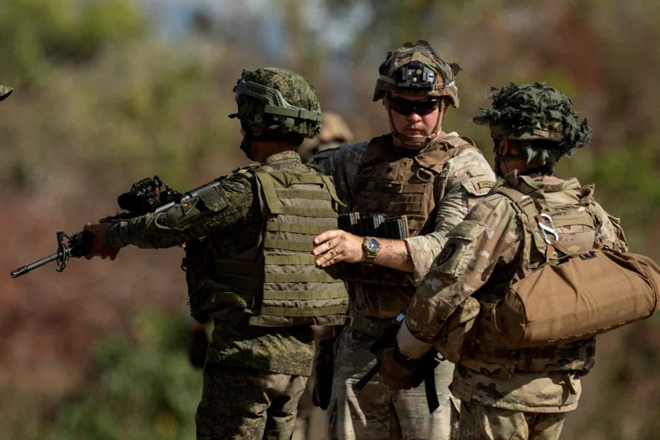A US soldier inspects the equipment of a Philippine soldier during a squad live fire exercise at the three-week joint military drills "Salaknib" in Fort Magsaysay, Nueva Ecija, Philippines, 31 March 2023. (Eloisa Lopez/Reuters)