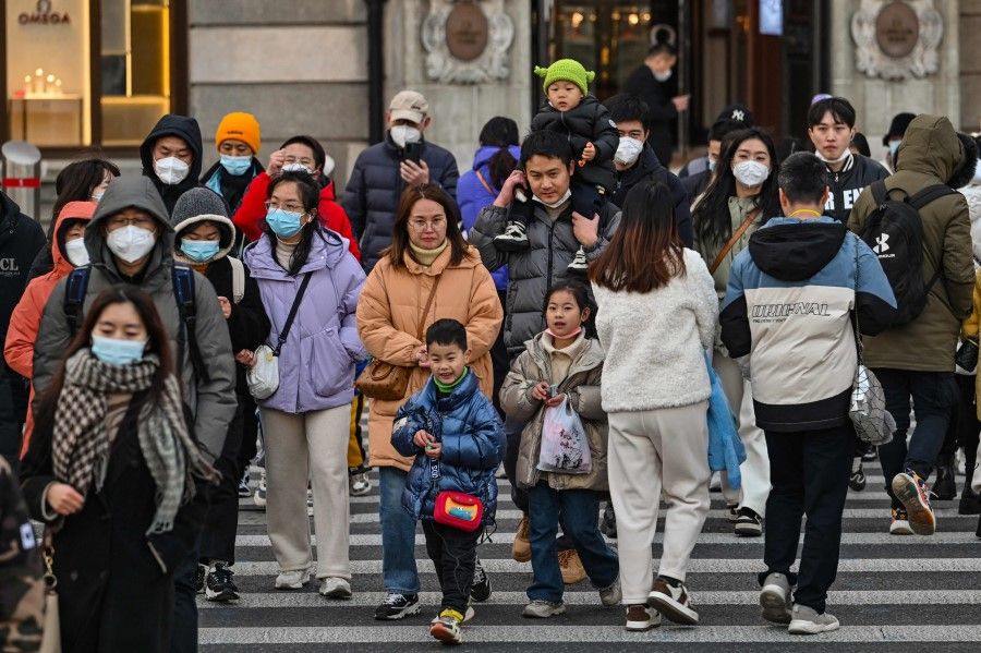 People cross a street on the Bund in the Huangpu district in Shanghai on 16 January 2023. (Hector Retamal/AFP)
