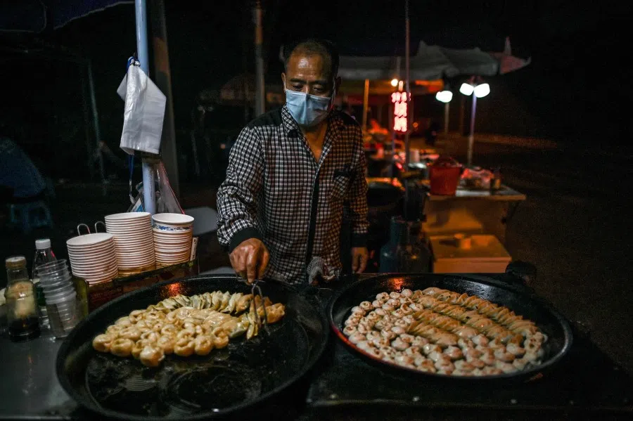 A man sells food at his stall on a street in Wuhan, 20 May 2020. (Hector Retamal/AFP)