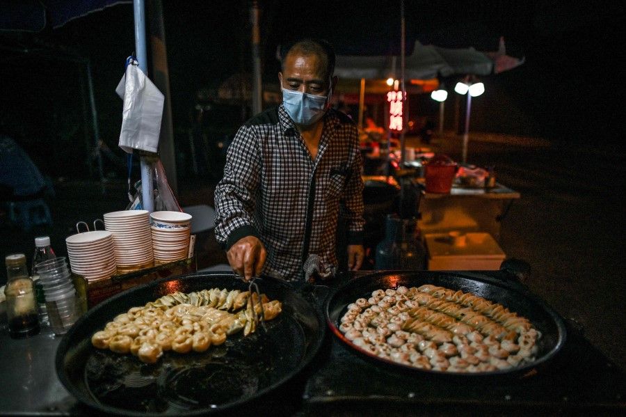 A man sells food at his stall on a street in Wuhan, 20 May 2020. (Hector Retamal/AFP)
