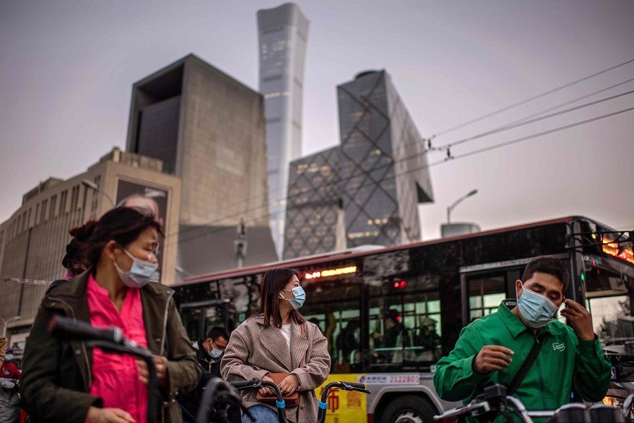People wearing face masks wait to cross a street during rush hour in Beijing on 21 October 2020. (Nicolas Asfouri/AFP)