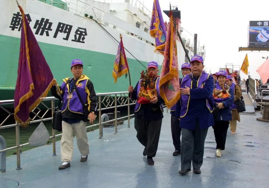 A Taiwanese Mazu pilgrimage group arrives in Xiamen by high-speed ferry from Kinmen before continuing onward to Meizhou Island, 2006. As they disembark, members carry statues of Mazu and hold aloft the pilgrimage banners.