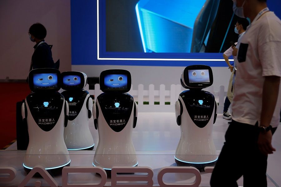 A man walks past robots at the Beijing World Robot Conference 2021 in Beijing, China, 10 September 2021. (Tingshu Wang/Reuters)