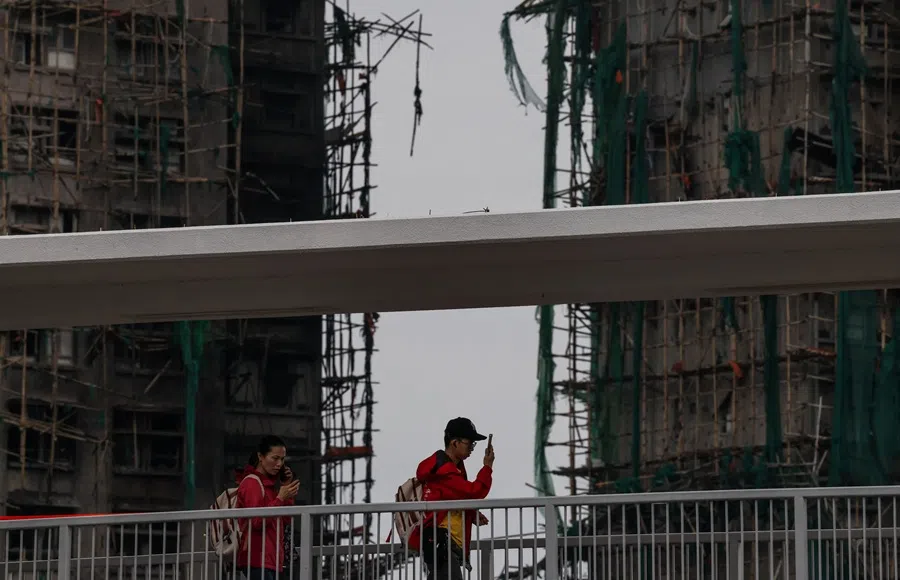 People walk along the pedestrian bridge next to the burned buildings of the Wang Fuk Court housing complex after the deadly fire, in Tai Po, Hong Kong, China, on 30 November 2025. (Maxim Shemetov/Reuters)