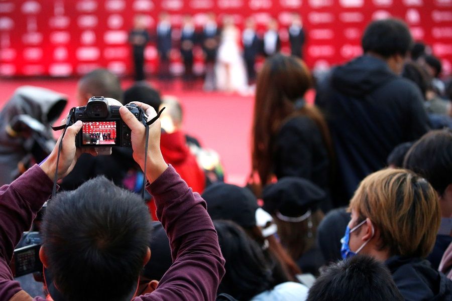 A man takes photos at a red carpet ceremony of the Beijing International Film Festival, in Beijing, China, 20 September 2021. (Tingshu Wang/Reuters)