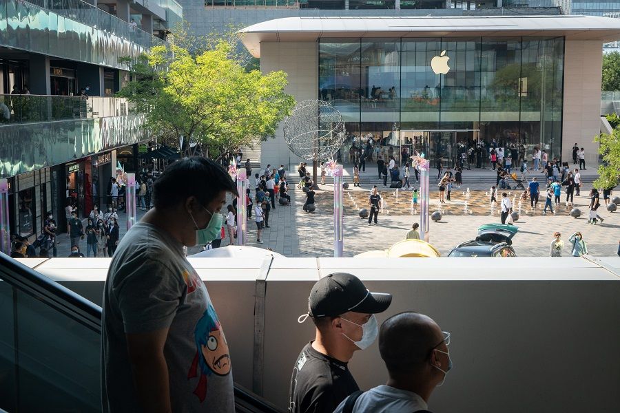 People wearing protective masks ride on an escalator as an Apple Inc. store stands at a shopping area in Beijing, China on 20 September 2020. (Yan Cong/Bloomberg)