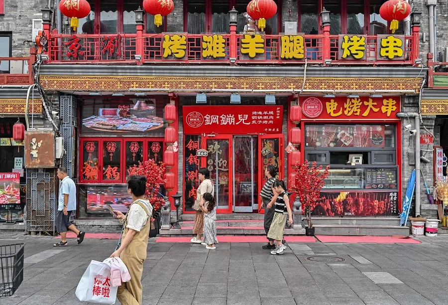 People walk along Huguosi Street, a dedicated food street in Beijing, China, 23 August 2024. (Adek Berry/AFP)