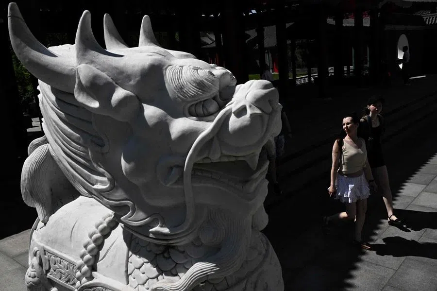 People walk past a statue of Chinese guardian lion in Huamin Park, the Chinese-style landscape park, in Moscow on 19 May 2026.