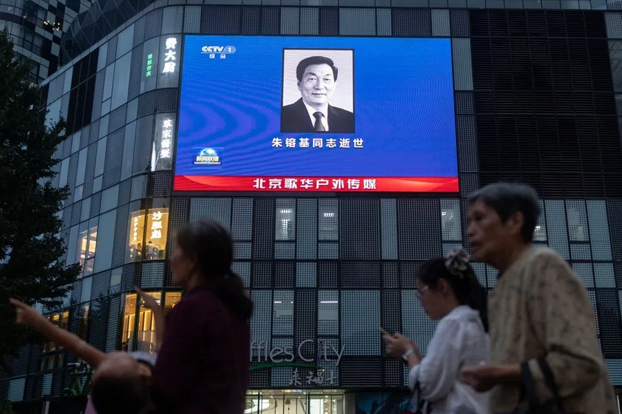 People walk next to a shopping mall featuring advertisement screen broadcasting a portrait of former Chinese Premier Zhu Rongji who passed away on 12 August 2026, in Beijing, China, on 12 August 2026.