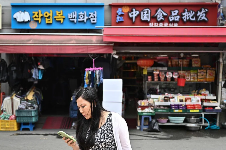 This picture taken on 28 May 2025 shows a woman checking her mobile phone in Seoul’s Daerim neighbourhood, home to thousands of ethnic Chinese.  (Pedro Pardo/AFP)