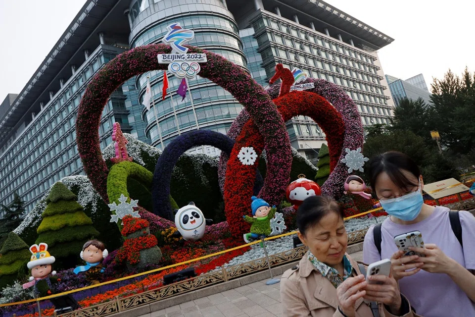 People check their phones near a Beijing 2022 Winter Olympics-themed floral installation set up ahead of the Chinese National Day, in Beijing, China, 30 September 2021. (Florence Lo/Reuters)