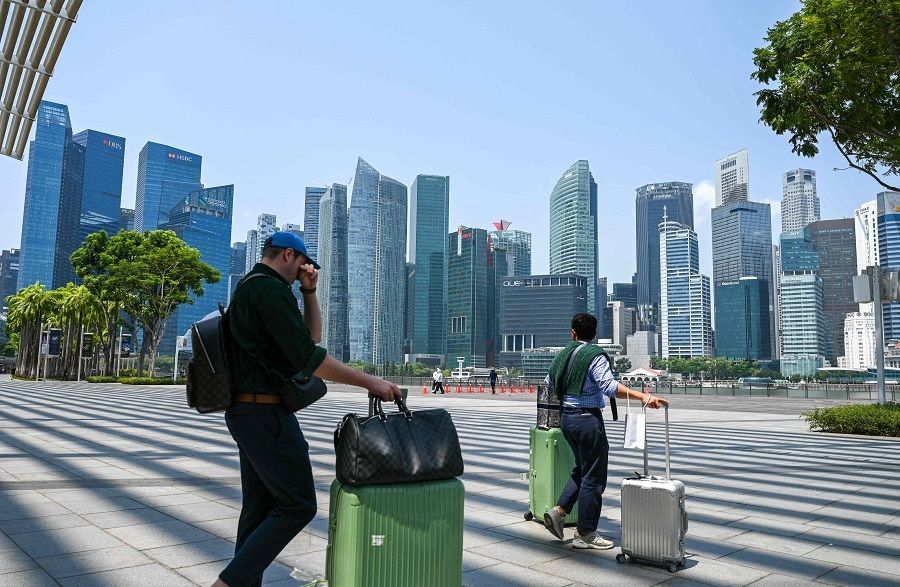 People with their luggage walk along the promenade at Marina Bay in Singapore on 13 October 2023. (Roslan Rahman/AFP)