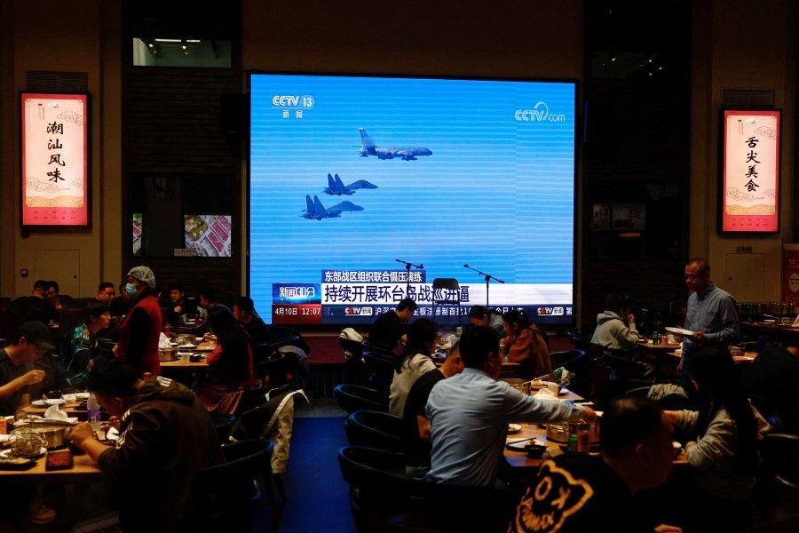 Customers dine near a giant screen broadcasting news footage of aircraft of the Air Force under the Eastern Theatre Command of China's People's Liberation Army (PLA) taking part in a combat readiness patrol and "Joint Sword" exercises around Taiwan, at a restaurant in Beijing, China, on 10 April 2023. (Tingshu Wang/Reuters)