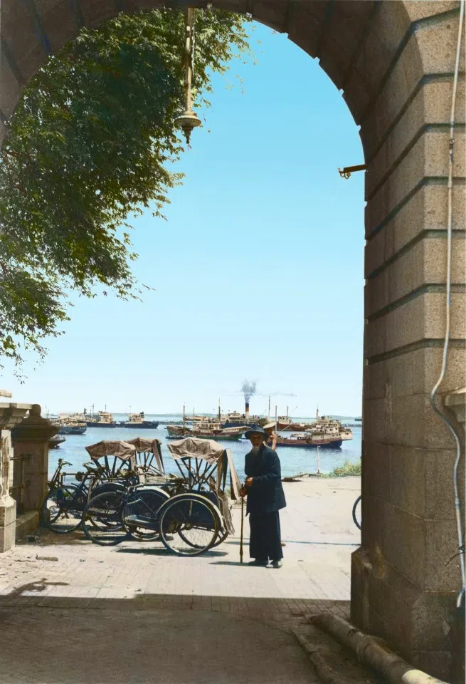 Trishaws at the port in Singapore, 1950s, presenting a serene waterside scene.