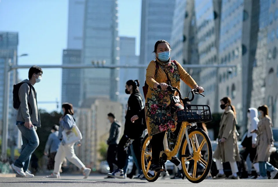 People walk along a street in Beijing, China, on 12 October 2021. (Noel Celis/AFP)