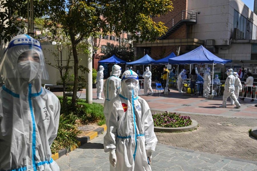 Workers and volunteers look on in a compound where residents are tested for the Covid-19 coronavirus during the second stage of a pandemic lockdown in Jing'an district in Shanghai on 4 April 2022. (Hector Retamal/AFP)