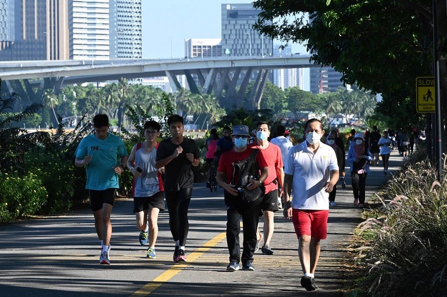 People walk and jog along the park connector at Marina Bay East as they enjoy the holiday to mark the country's National Day holiday in Singapore on 9 August 2021. (Roslan Rahman/AFP)