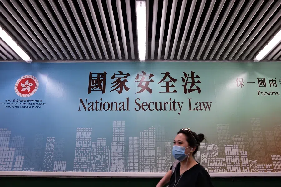 A woman walks past a poster for the National Security Law in Hong Kong on 28 July 2020. (Anthony Wallace/AFP)