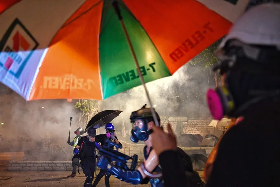 Pro-democracy protesters react from tear gas fired by the police outside Tsim Sha Tsui Police station during a demonstration against the controversial extradition bill in Hong Kong, China, on 11 August 2019. (Manan Vatsyayana/AFP)