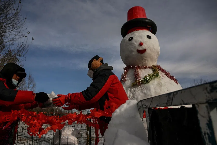 Workers build a snowman at a park after a light snowfall overnight in Beijing, China, on 23 January 2023. (Noel Celis/AFP)