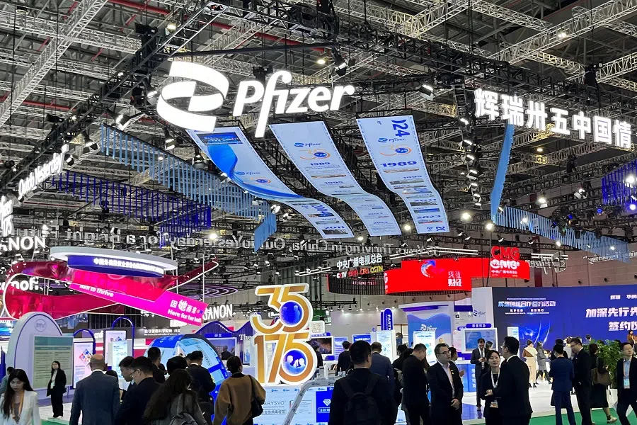 People walk past the booth of drug maker Pfizer booth at the China International Import Expo (CIIE) in Shanghai, China, 7 November 2024. (Andrew Silver/Reuters)