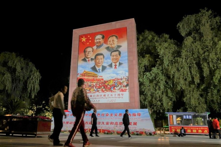 People walk past a poster showing Chinese President Xi Jinping and former Chinese leaders Mao Zedong, Deng Xiaoping, Jiang Zemin and Hu Jintao on the Potala Palace Square during a government-organised media tour to Lhasa, Tibet Autonomous Region, China, 1 June 2021. (Martin Pollard/Reuters)