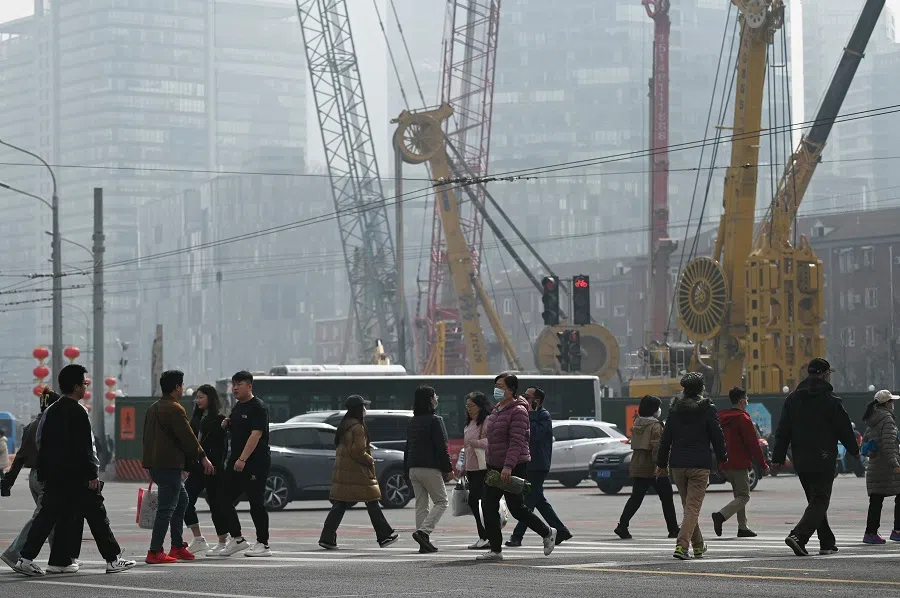 People cross a road in Beijing, China, on 16 March 2024. (Greg Baker/AFP)